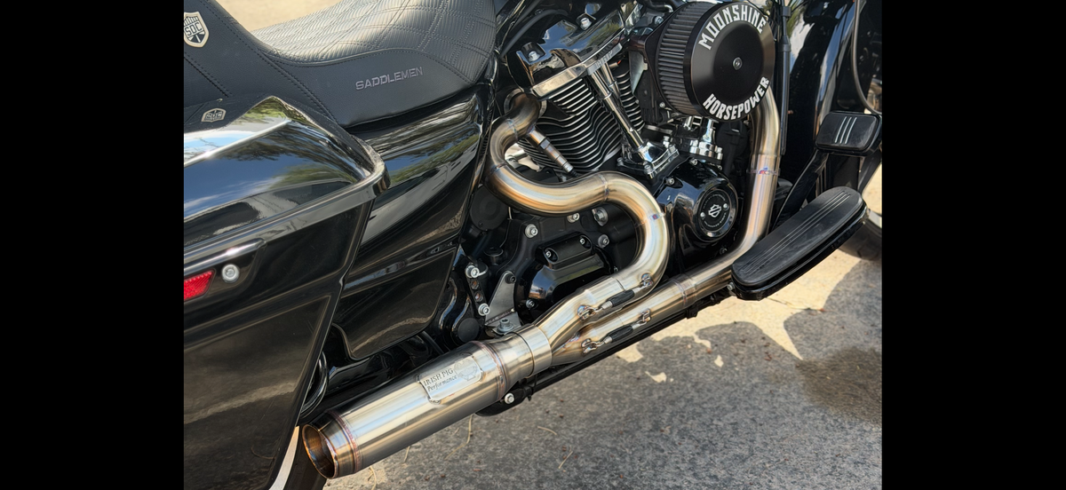 Close-up of Irish Pig Performance Harley-Davidson Road Glide 2-Into-1 mid-length exhaust showing stepped stainless-steel primaries and merge collector