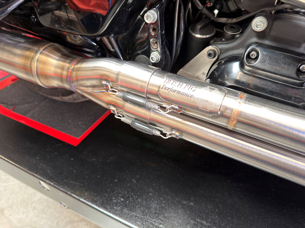 Close-up of Irish Pig Prformance Harley-Davidson Road lide full-length 2-Ino-1 exhaust showing stainless-steel collector section and spring-retained slip joints